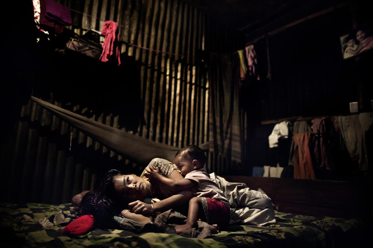 Mother and son at the Manda slum, in Dhaka.Around the capital city of Dhaka, huge shanty towns made of iron sheets and plastic have sprung without any electricity, gas or water, let alone a sewage system, surrounded by piles of garbage where undisturbed dogs, goats and cows scavenge for food. Bangladesh 2010